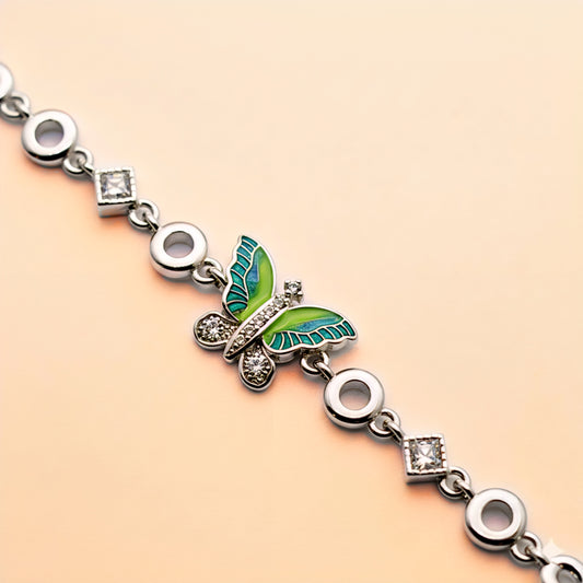 Silver bracelet with a green butterfly charm on a beige background