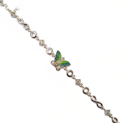 Silver bracelet with a green butterfly charm on a white background